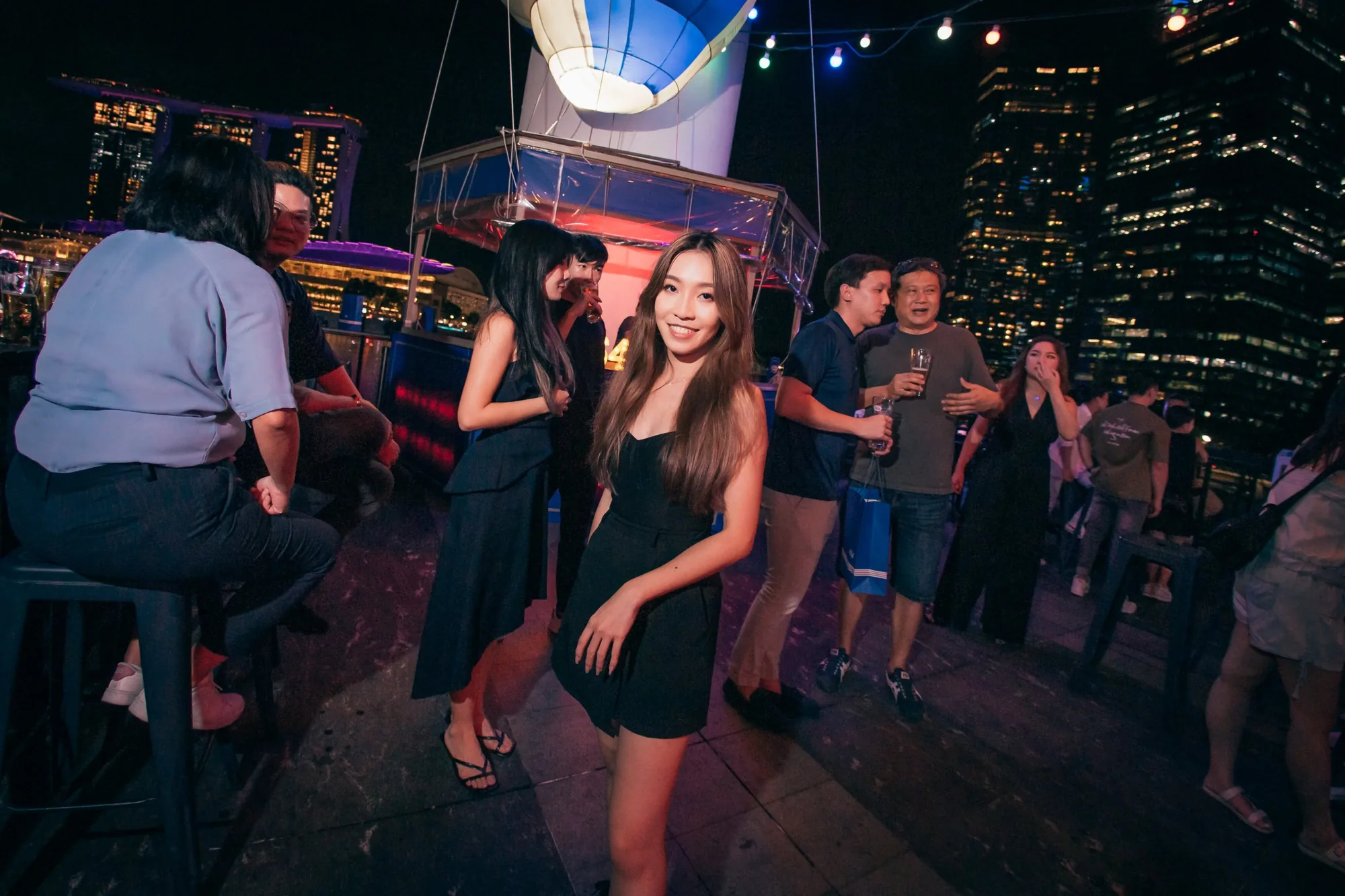 A guest on the rooftop, with the hot air balloon bar and Marina Bay Sands behind