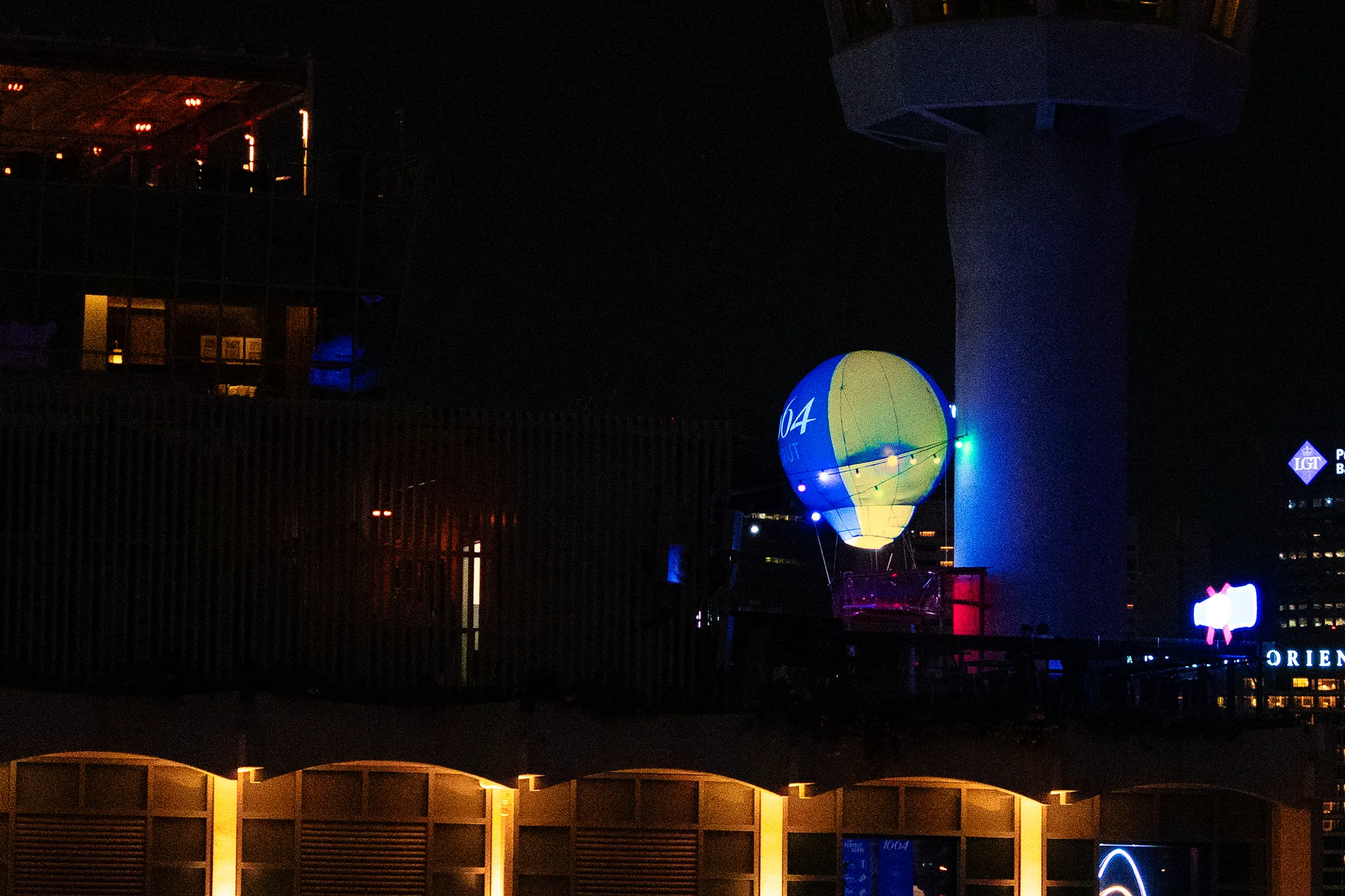 The 1664 Brut hot air balloon glowing on the rooftop at night, seen from across the bay
