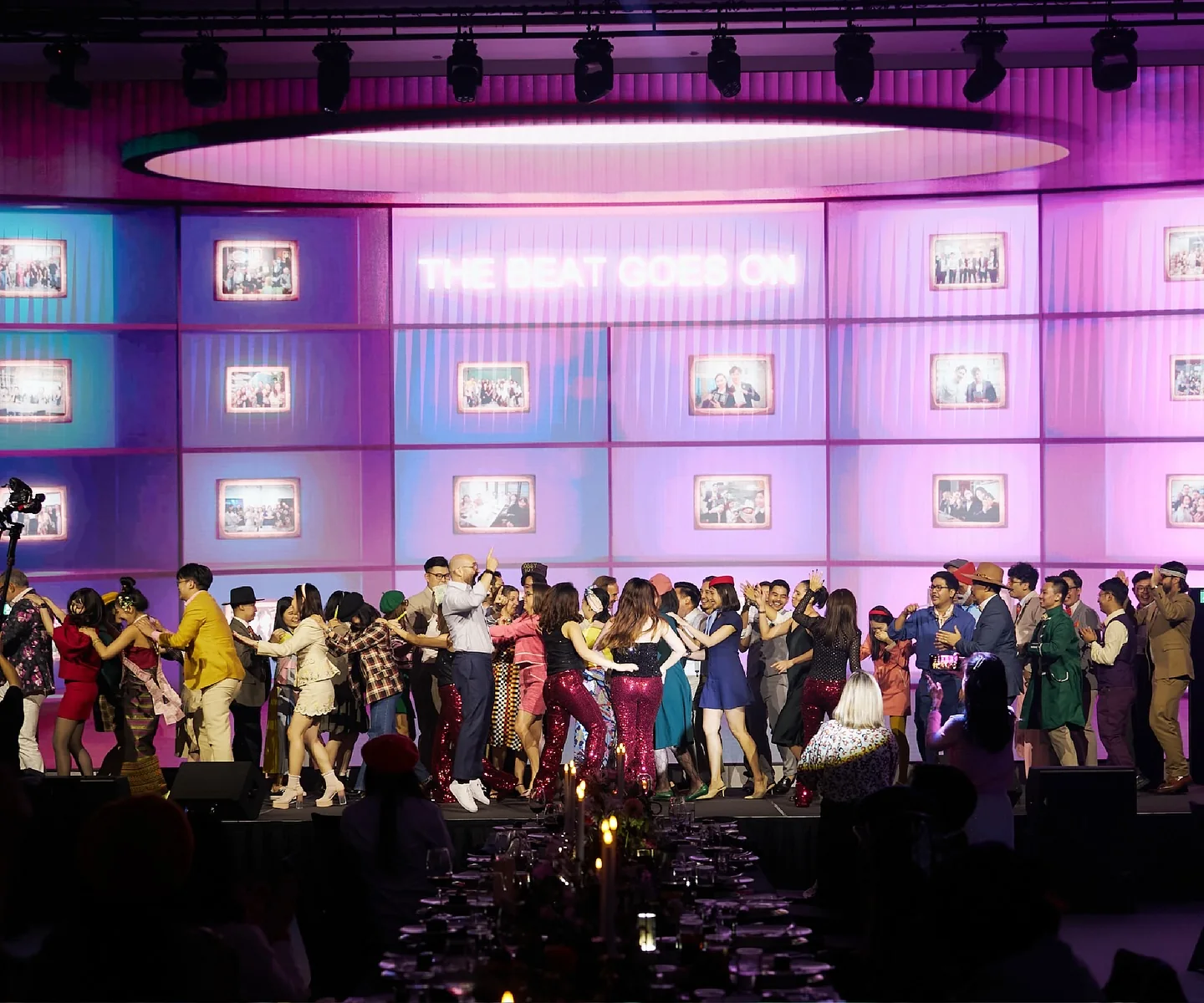 Staff dancing on stage under the party screens