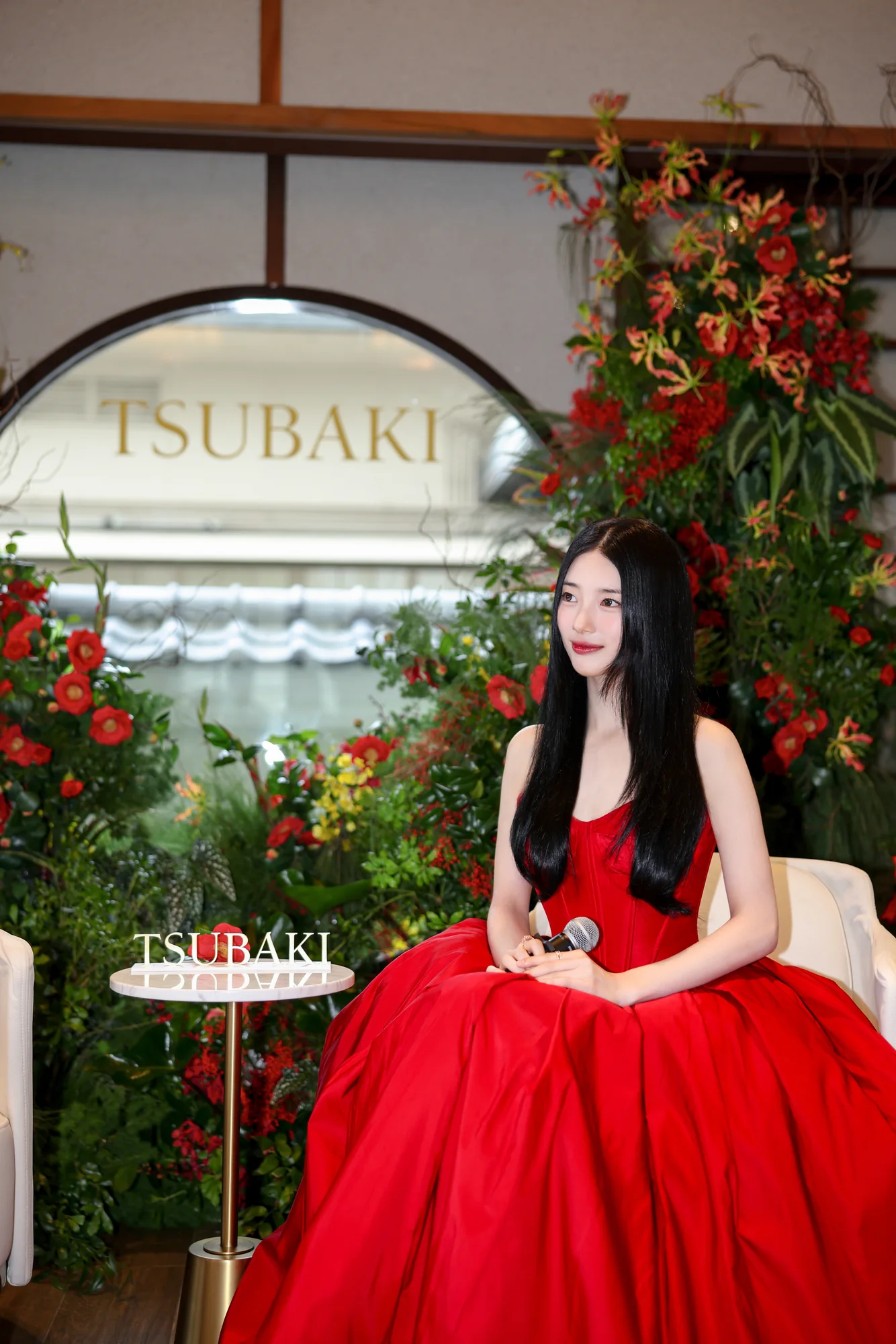 Suzy Bae seated in the garden pavilion under the TSUBAKI sign